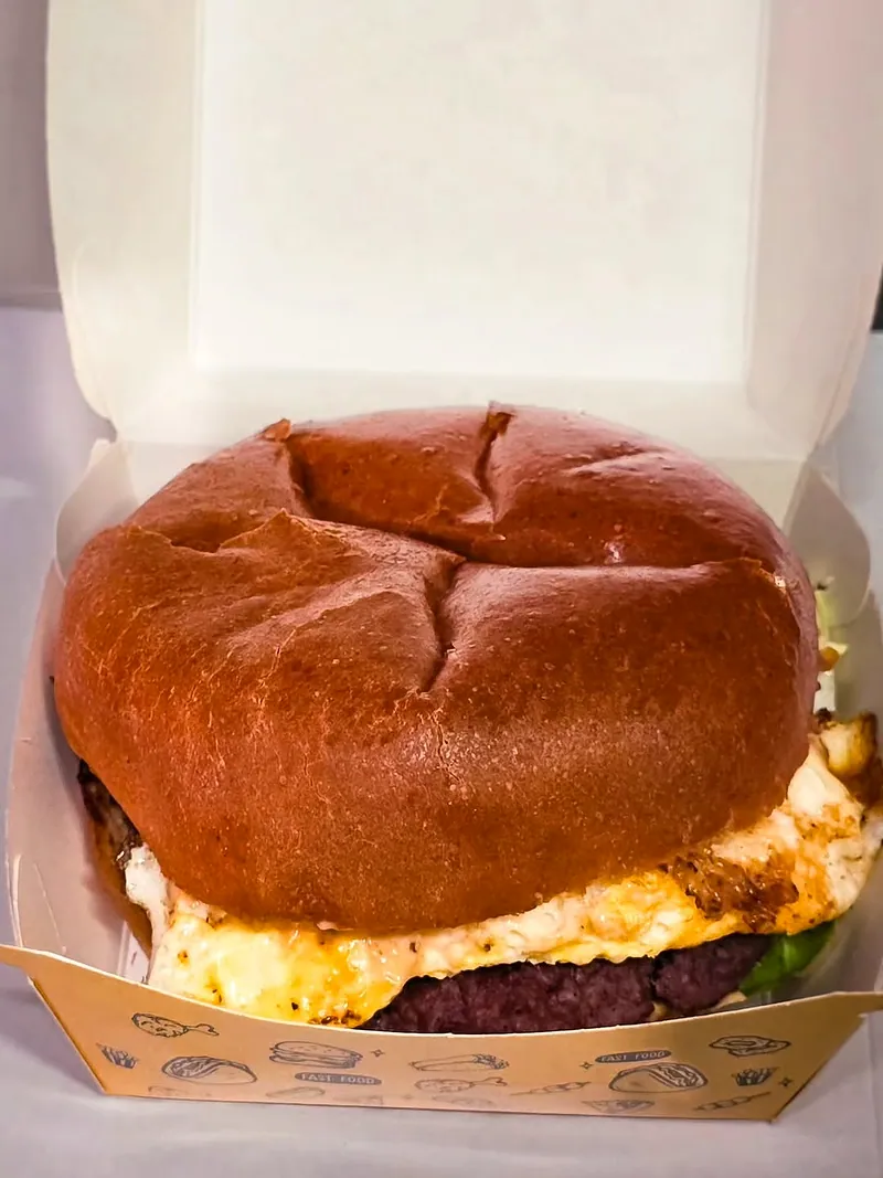 Burger au pain brioché doré dans une boîte en carton ouverte